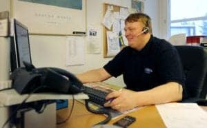 Kundtjänstmedarbetare med headset arbetar vid dator i ett kontor.