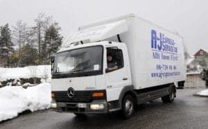 Flyttbil med företagsnamn och kontaktuppgifter i vinterlandskap.