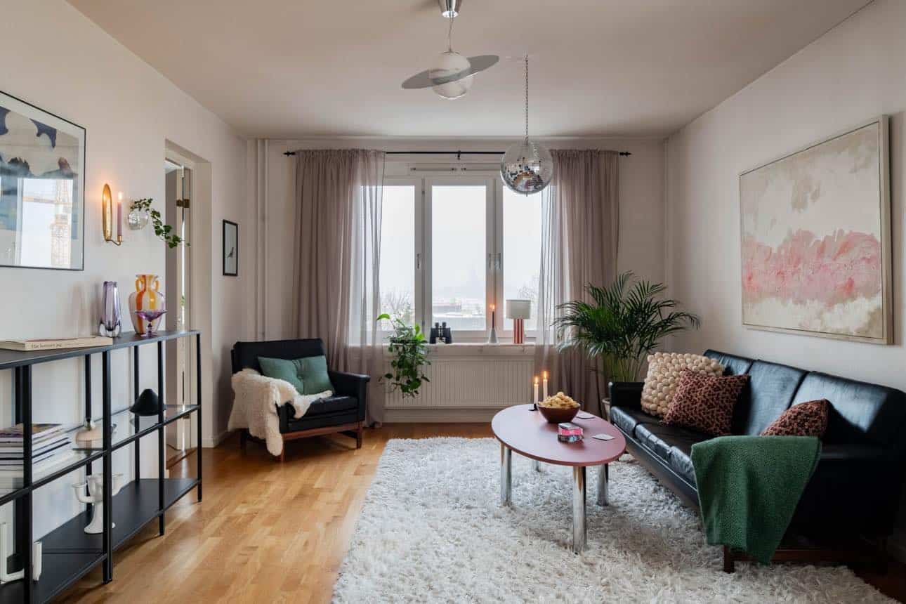 Vardagsrum med stilren inredning, stora fönster och ljusa väggar.