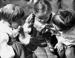 Tre barn som leker tillsammans utomhus i midsommartid.