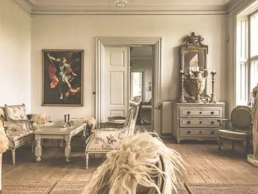 Antika möbler i ett elegant vardagsrum med spegel och sittplatser.